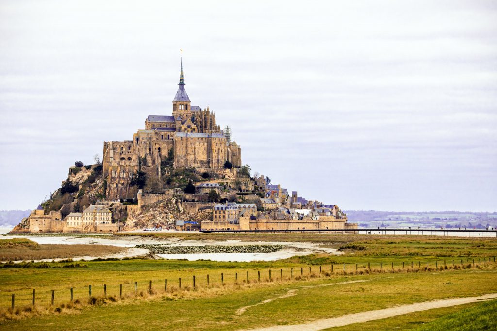 Discover Mont Saint-Michel, a stunning French landmark against an overcast sky, ideal for travel enthusiasts.