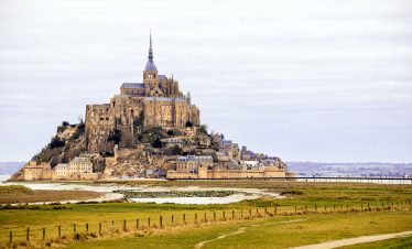 Discover Mont Saint-Michel, a stunning French landmark against an overcast sky, ideal for travel enthusiasts.