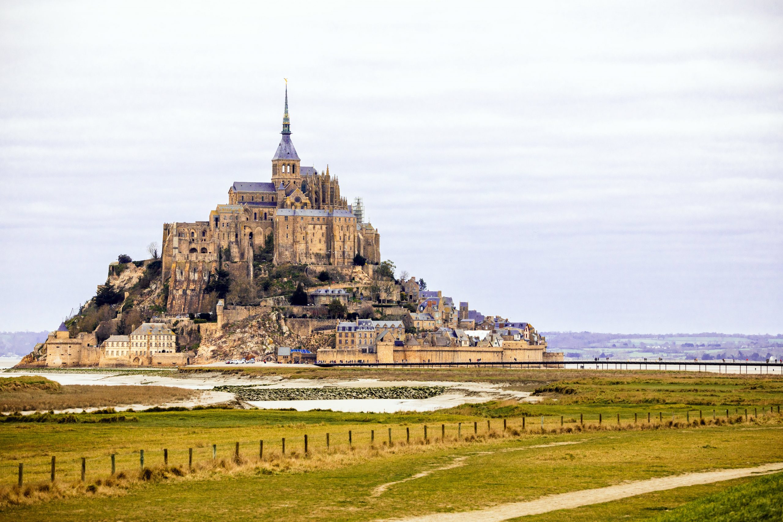 Discover Mont Saint-Michel, a stunning French landmark against an overcast sky, ideal for travel enthusiasts.