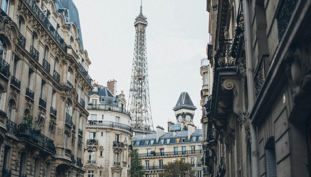 Scenic view of the Eiffel Tower framed by classic Parisian architecture on a charming street.