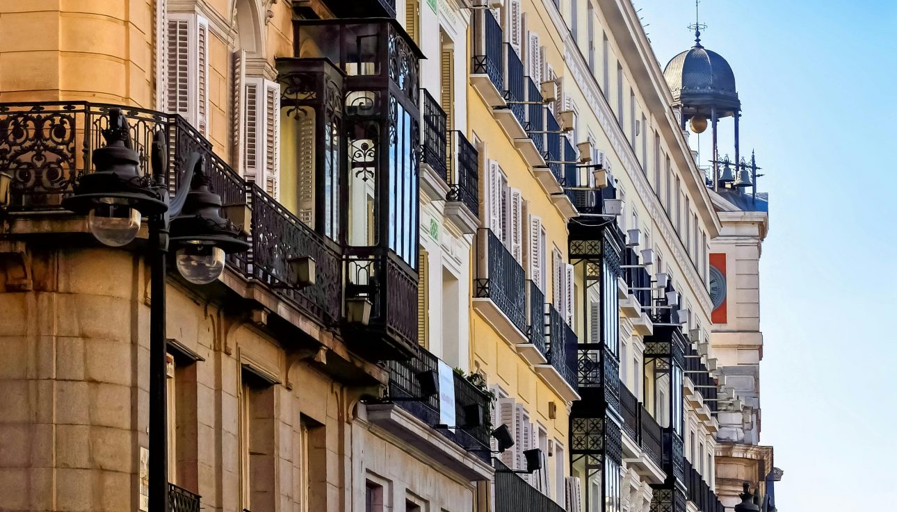 Elegant historic buildings and ornate balconies in a vibrant Madrid street scene.