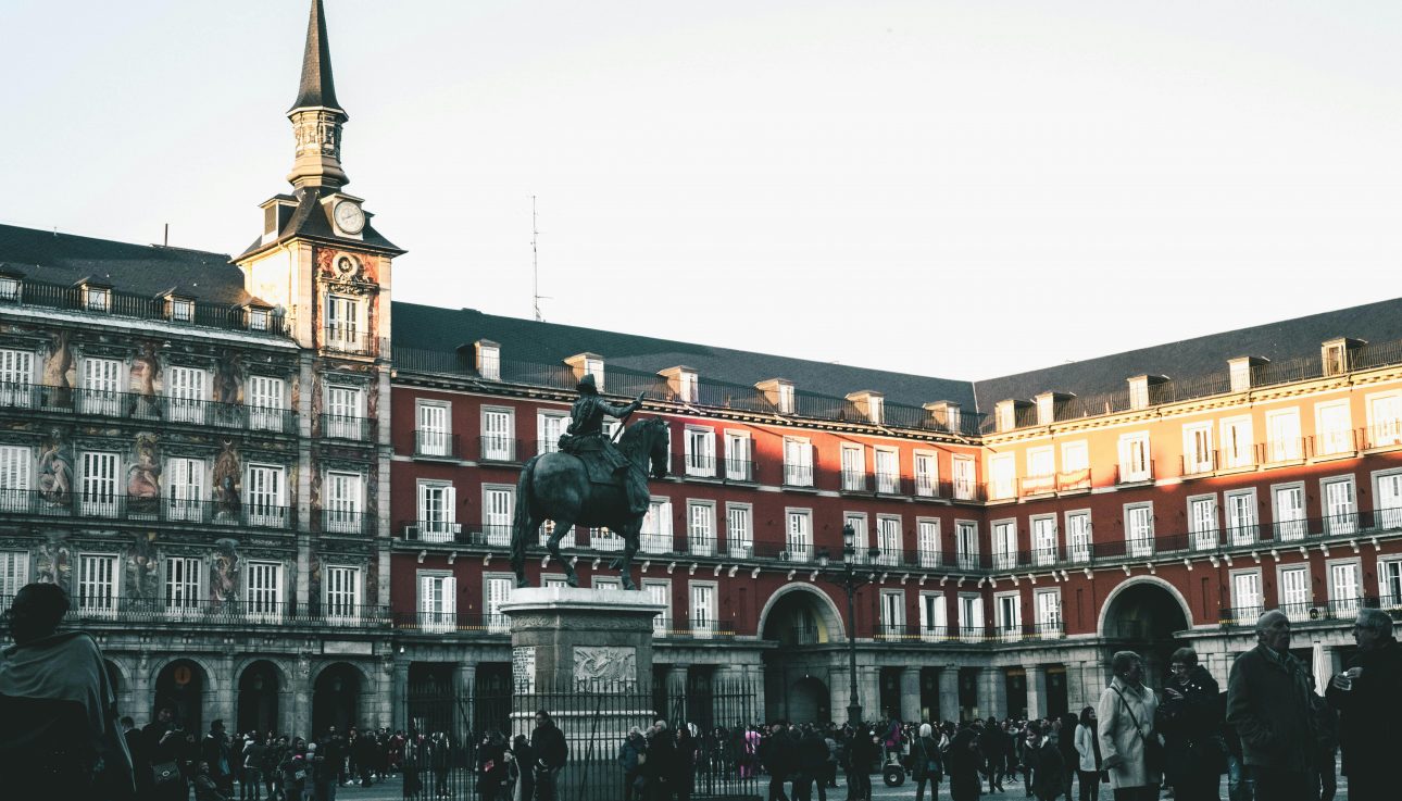 A lively scene at Plaza Mayor, Madrid, featuring historic architecture and a statue.